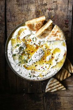 a bowl filled with hummus and pita bread on top of a wooden table