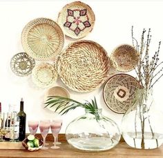 there are many wicker baskets on the wall and vases in front of it