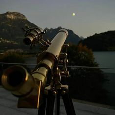 a telescope sitting on top of a wooden tripod next to a body of water