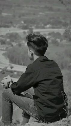 a young man sitting on top of a hill