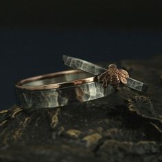 two wedding rings sitting on top of a rock next to each other, one with a bee in it's center