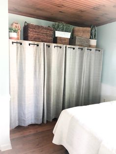 a bed sitting under a wooden ceiling next to two baskets on top of a shelf