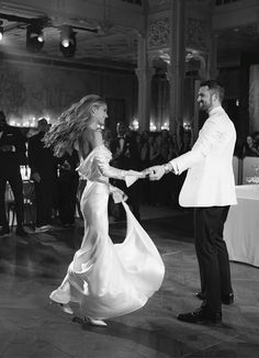 a bride and groom dancing on the dance floor at their wedding reception in black and white