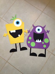 two paper monsters standing next to each other on a tile floor in front of a tiled floor