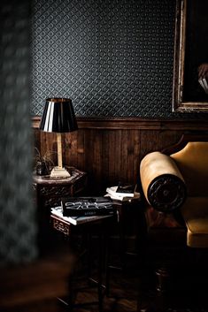 a chair and table in a dark room with a painting on the wall behind it