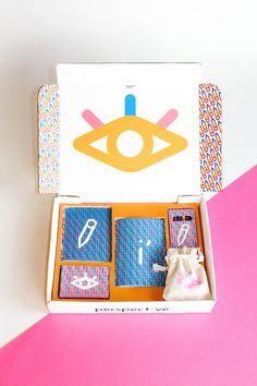 an open box with four cards in it on a pink and white tableclothed surface