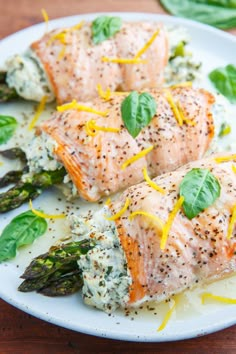 two salmon fillets with asparagus and spinach garnish on a white plate