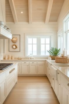 a large kitchen with white cabinets and wood flooring on the walls, along with an island in the middle