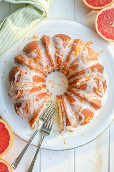 a grapefruit bundt cake with icing on a white plate next to sliced grapefruits