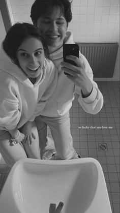 a man and woman are taking a selfie in the bathroom sink with their cell phone