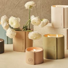 three vases with flowers in them sitting on a table next to books and candles