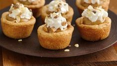 small cupcakes with whipped cream and nuts on a black plate, ready to be eaten