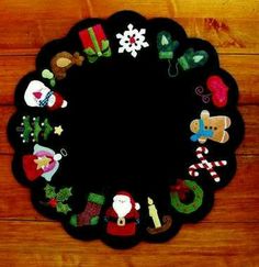 a christmas wreath made out of felt on top of a wooden floor with decorations around it