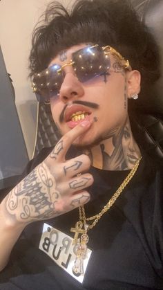 a man with tattoos and piercings on his face is sitting in a car wearing sunglasses