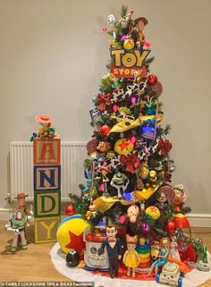 a toy christmas tree with toys around it and an assortment of other ornaments on top