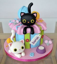 a birthday cake with a cat on top and toys around the edges, including an animal figurine