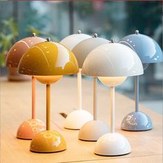 several different colored lamps sitting on top of a wooden table