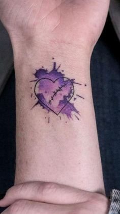 a woman's wrist with a purple heart tattoo on it