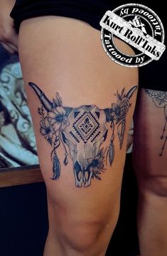 a woman's thigh with an animal skull and flowers on it