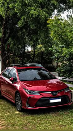 a red car parked in front of some trees