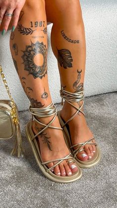 a woman with tattoos on her legs and foot is sitting next to a handbag