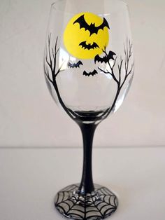 a wine glass decorated with bats and trees