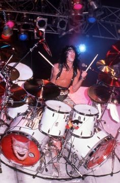 a man with long hair playing drums on stage