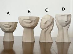 four different shapes and sizes of clay heads on a table with the letters abc, c, d