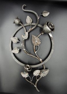 a metal sculpture with flowers and leaves on it