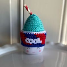 a crocheted hat with a toothbrush sticking out of it on top of a cup