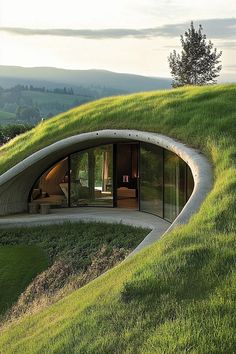 an unusual house on top of a hill with grass growing all over the sides and windows