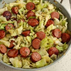 a pan filled with cabbage and sausages on top of a table