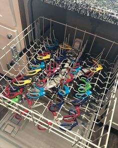 a dishwasher filled with lots of different colored scissors