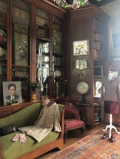 an old man sitting on a couch in a room with bookshelves and pictures