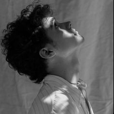 a black and white photo of a woman with curly hair looking up to the sky