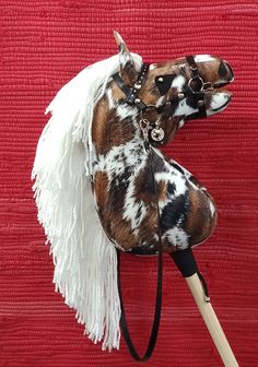 a brown and black spotted horse with white fringe on it's head is standing in front of a red background