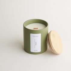 a green candle with a wooden lid next to it