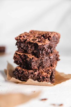 three chocolate brownies stacked on top of each other with one piece cut in half