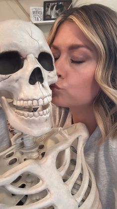 a woman kissing a skeleton in front of her face