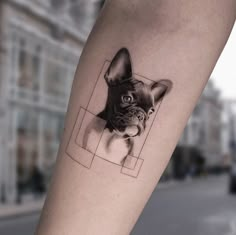 a small black and white dog tattoo on the right arm, with an image of it's face