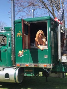 a woman sitting in the drivers seat of a green truck with an american flag on it