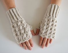 two hands with crocheted gloves on top of each other and one hand in the middle