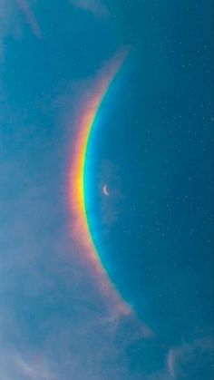 a rainbow colored object in the sky with stars on it's sides and a moon behind it