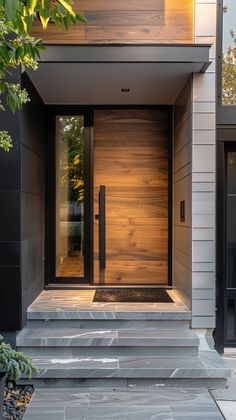 the front door to a modern home with wood paneling and stone steps leading up to it