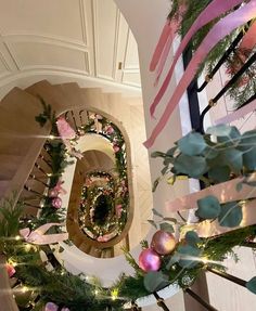 the stairs are decorated with pink and green garlands, christmas ornaments, and ribbons