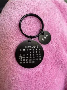 a pink blanket with a black keychain that has a round tag on it