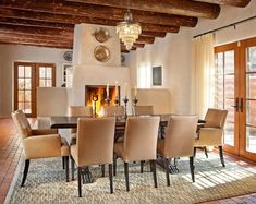 a dining room table with chairs and a fire place in the fireplace behind it is surrounded by windows