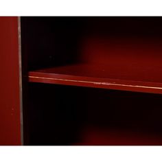 an empty shelf in the corner of a room with red walls and wood trimmings