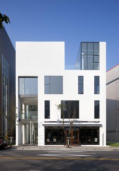 an empty street in front of a white building with lots of windows on each side