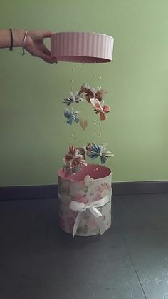 a person is throwing butterflies into a pink box with white ribbon on the top and bottom